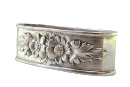 Argola de guardanapo em prata de forma oval com flores relevadas.